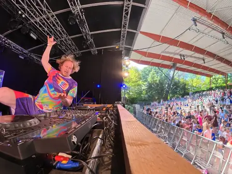 Kinder-DJ Blijwin® draait op een groot podium voor een volle openluchttheatertribune