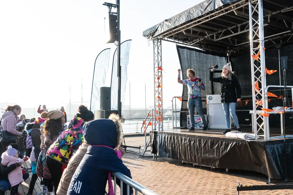 Kinderen kijken en doen mee bij een muziekoptreden op een buitenpodium