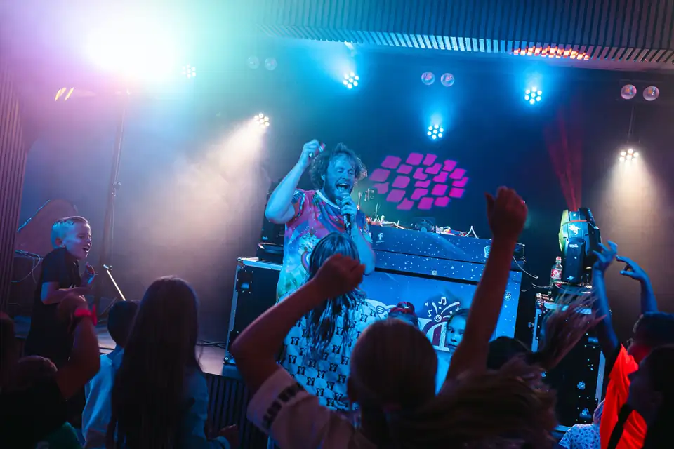 DJ Blijwin® met microfoon tussen dansende kinderen op een communiefeest
