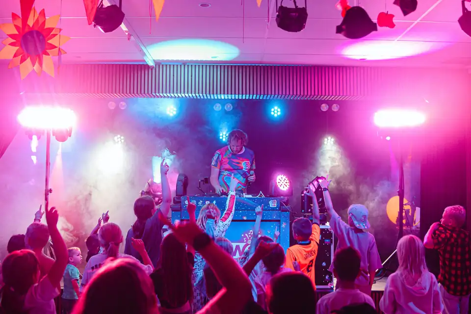 Kinderen met handen in de lucht tijdens een indoor Blijwin® kinderdisco